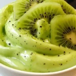 Close-up of Pistachio Luxe Cream topped with fresh kiwi slices in a white bowl