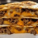 Burger Quesadillas:Amateur-style photo of freshly grilled burger quesadillas on a kitchen counter, showing melted cheese and seasoned beef between golden-brown tortillas, taken with an iPhone 11 in warm natural lighting.