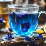 Butterfly Pea Flower Tea:Close-up view of a transparent glass mug filled with vibrant blue Butterfly Pea Flower Tea, with whole purple butterfly pea flowers floating on the surface. The mug is set on a rustic wooden surface, surrounded by scattered dried butterfly pea flowers, a wooden honey dipper, and fresh yellow lemon halves. Soft, warm natural light highlights the vivid blue color of the tea and the delicate texture of the flowers.